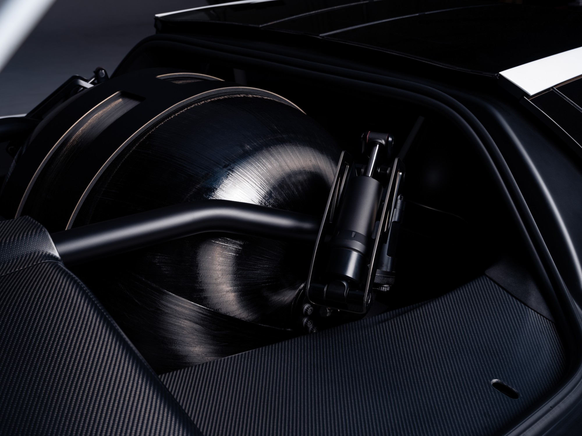 A black, carbon-wrapped spherical pressure vessel mounted inside the Roadster’s carbon-fibre rear structure, next to a suspension damper